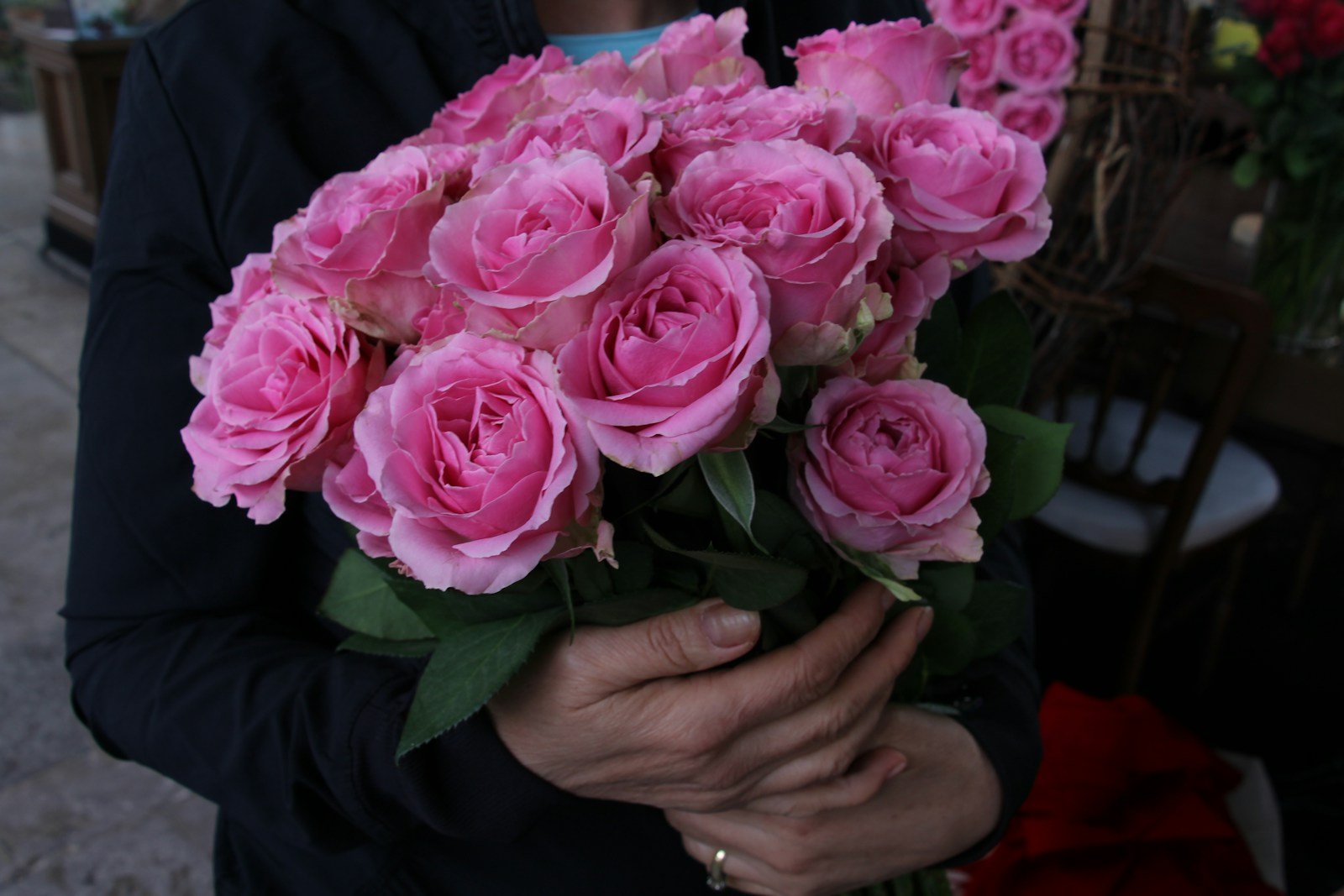 Fleuriste tenant une tige de rose branchue à plusieurs boutons
